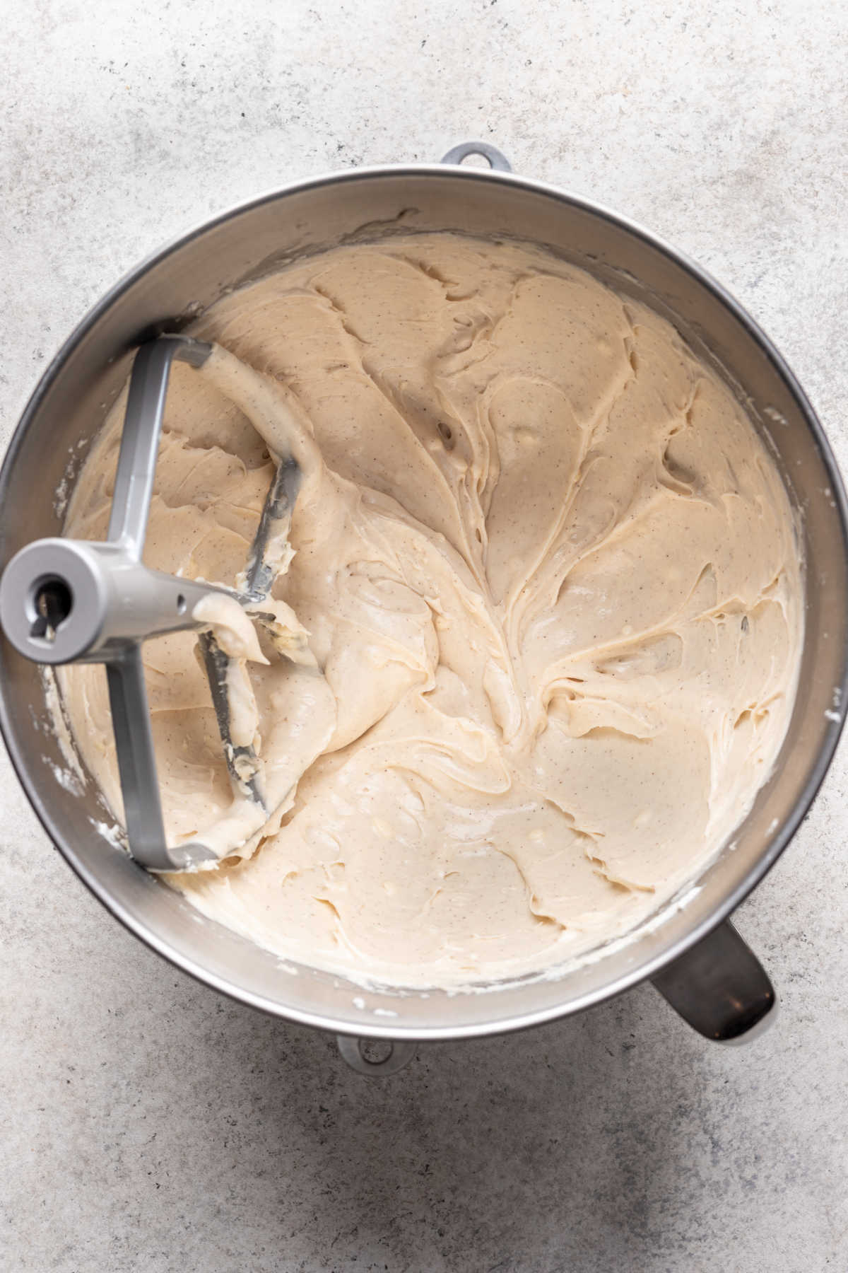 Glaçage au fromage à la crème pour roulés de pain d'épices dans un bol de mélange en métal.