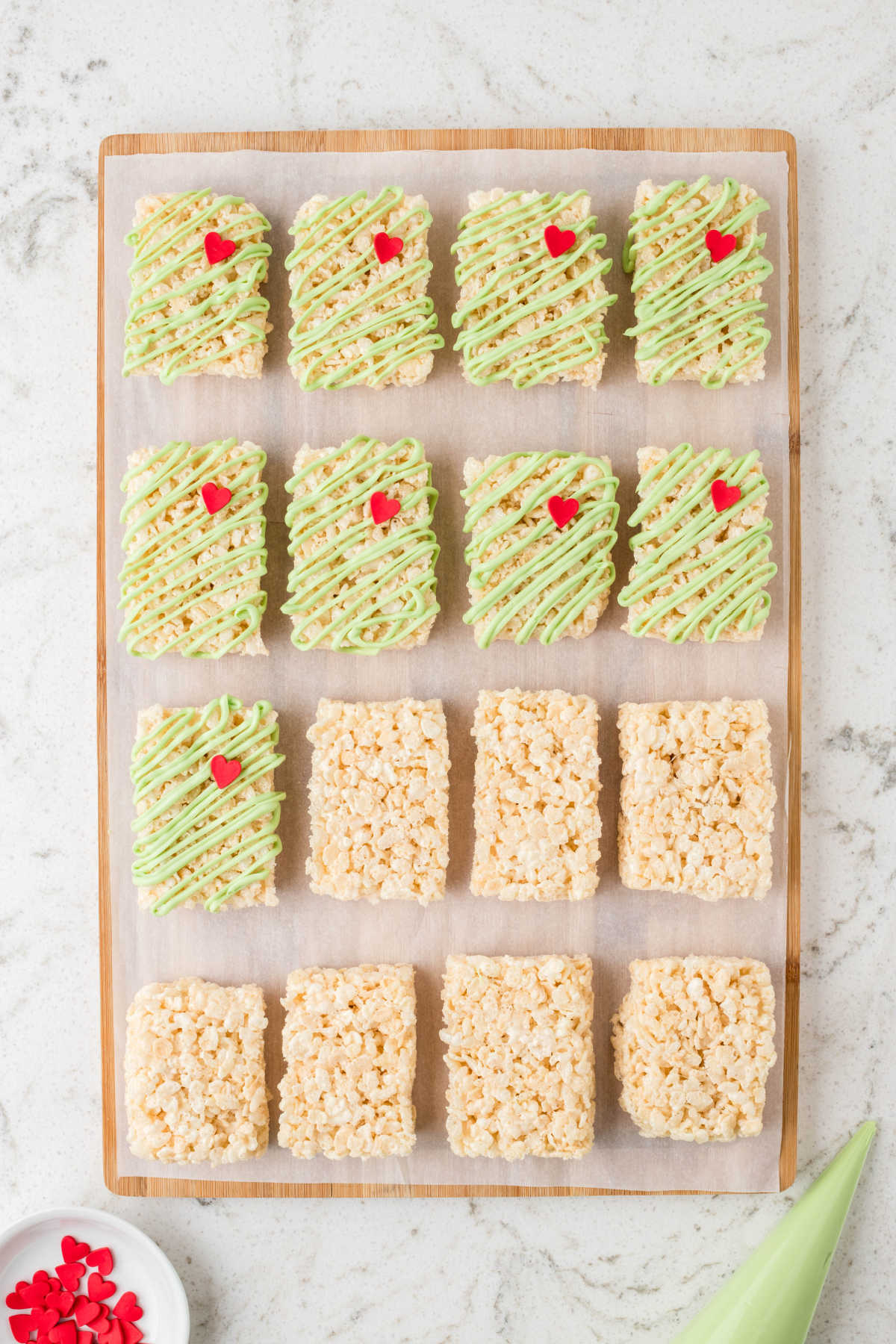 Corta el arroz krispie en una hoja de pergamino con la mitad de ellos regados con dulces verdes. 