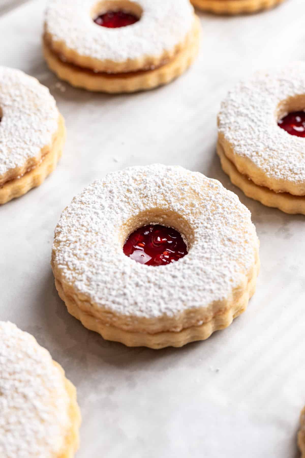 A row of linzer cookies on a piece of parchment paper. 