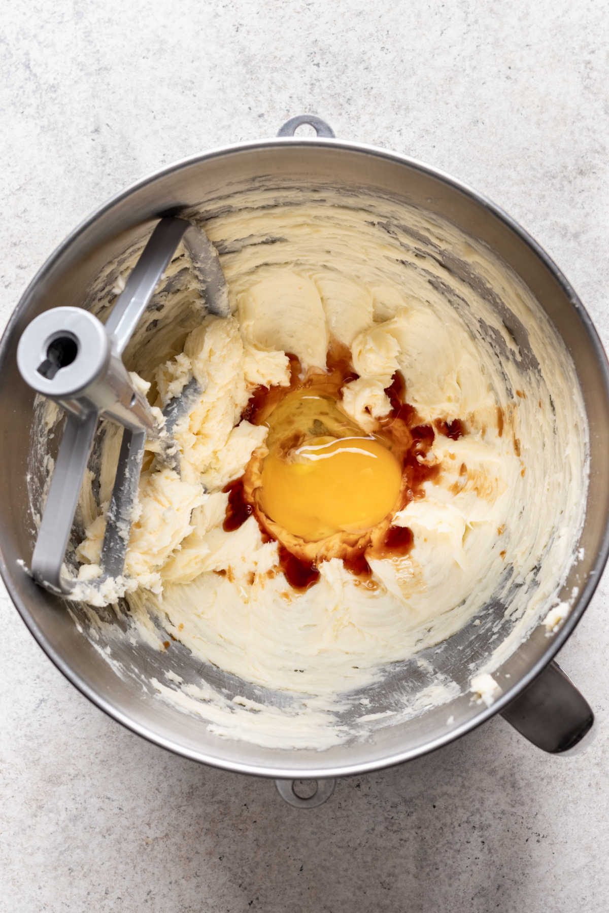 Egg and vanilla on top of creamed butter and sugar in a mixing bowl. 