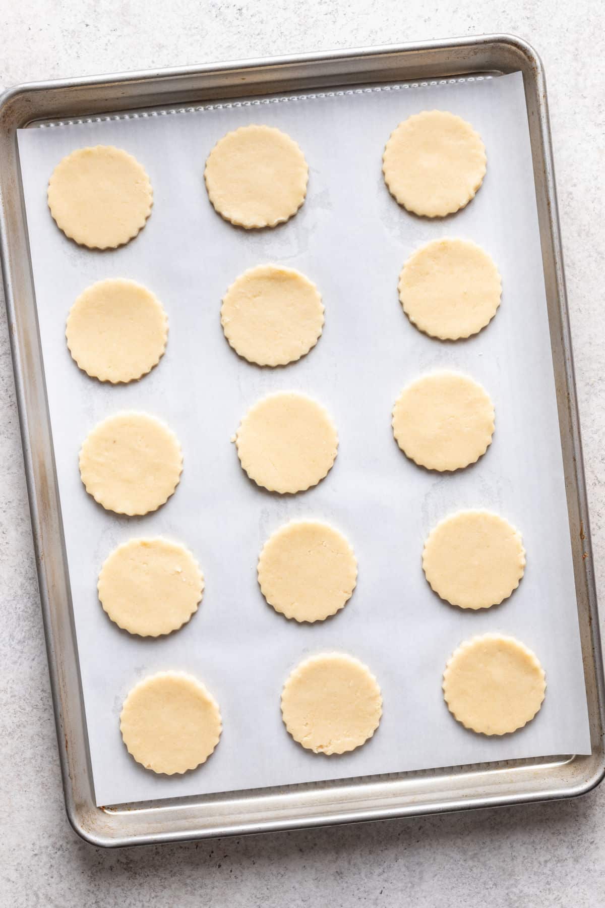 Cercles de pâte à biscuits Linzer sur une plaque de cuisson tapissée de papier sulfurisé.