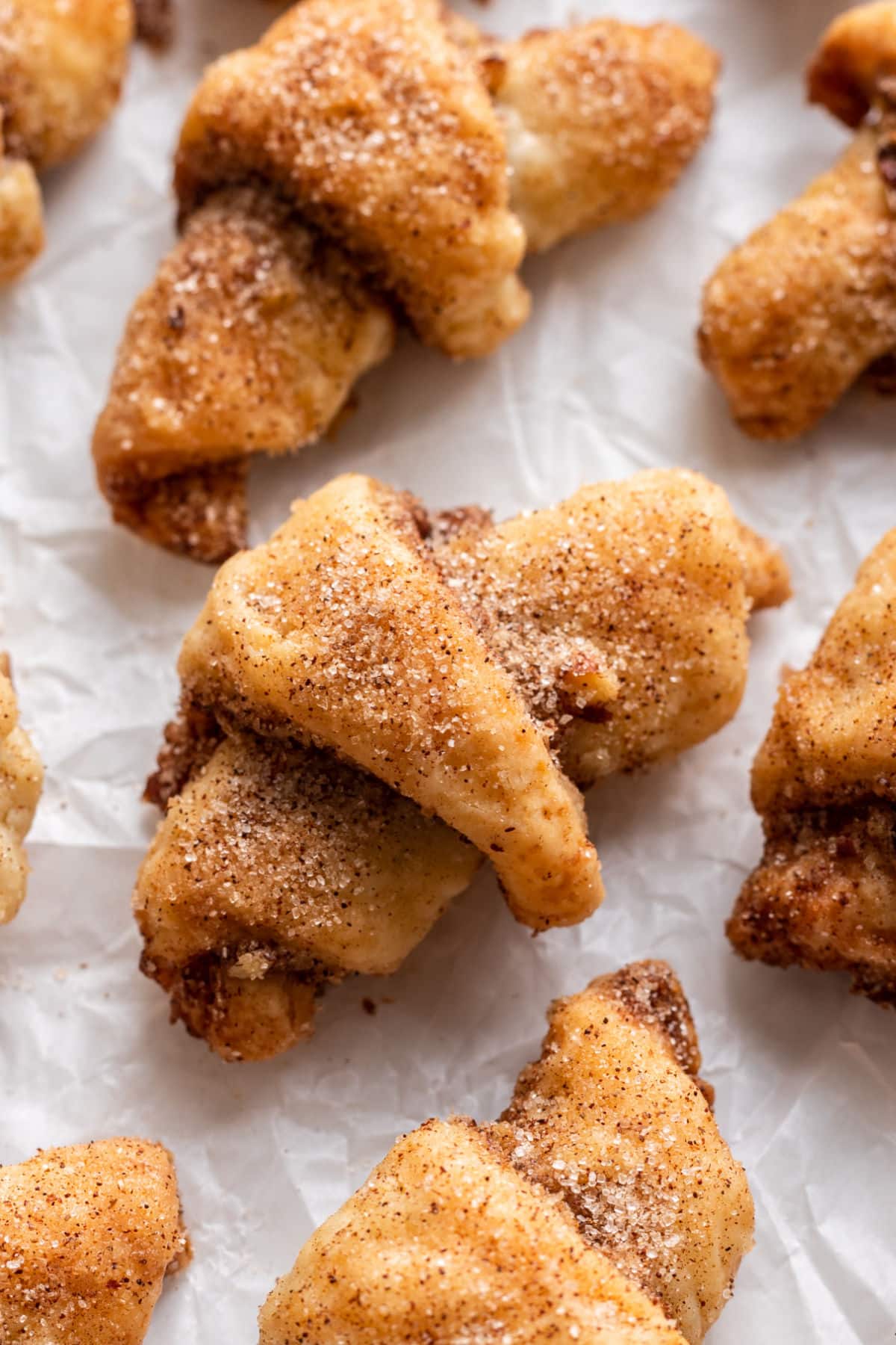 Rugelach au sucre de cannelle en rangées sur un papier sulfurisé.