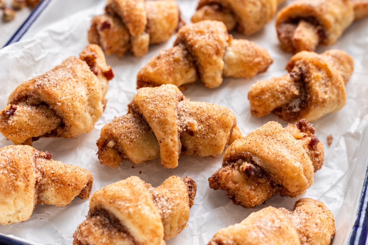 Rugelach sur du papier sulfurisé à côté d'une plaque de cuisson.