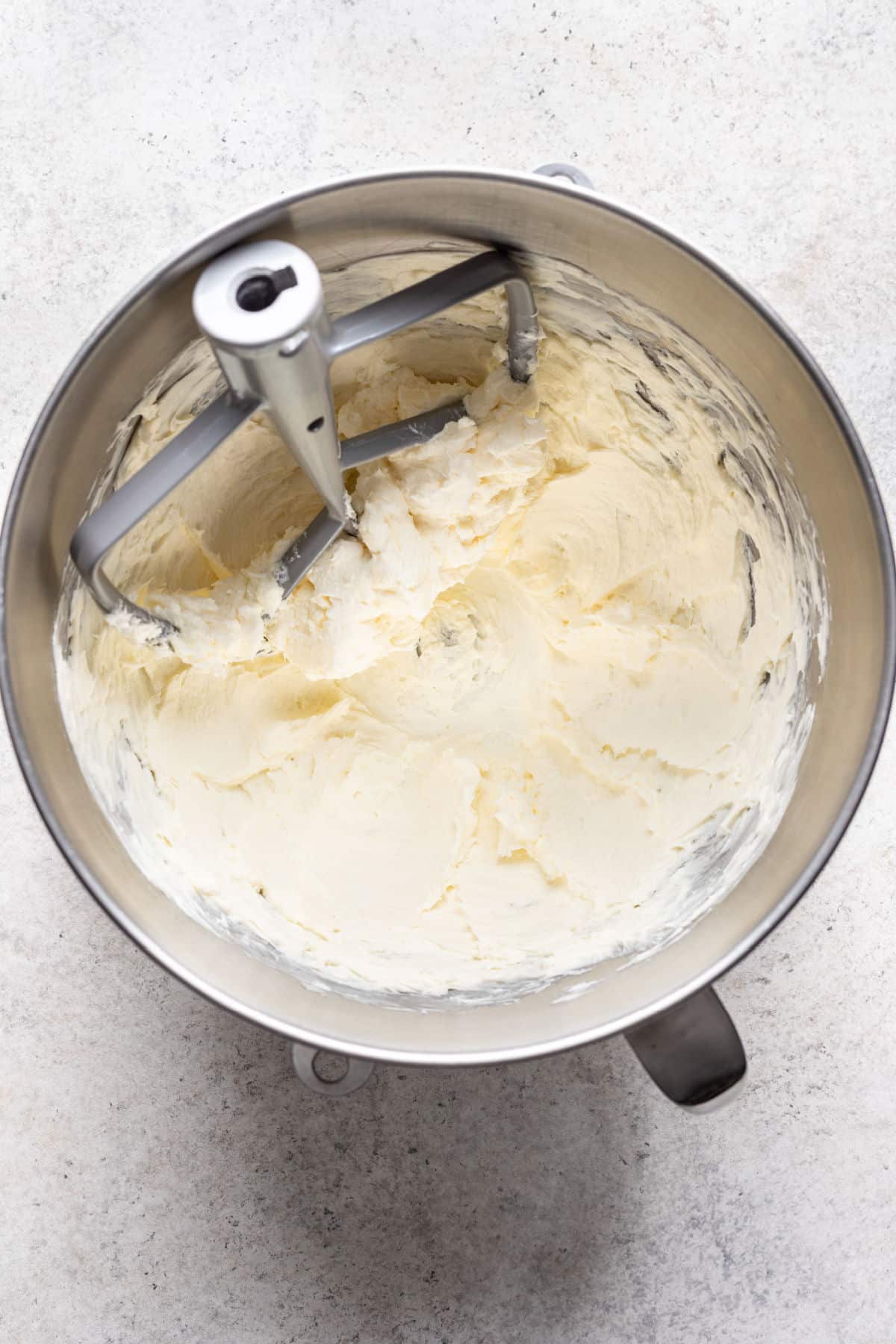 Beurre et fromage à la crème battus ensemble dans un grand bol à mélanger en acier.