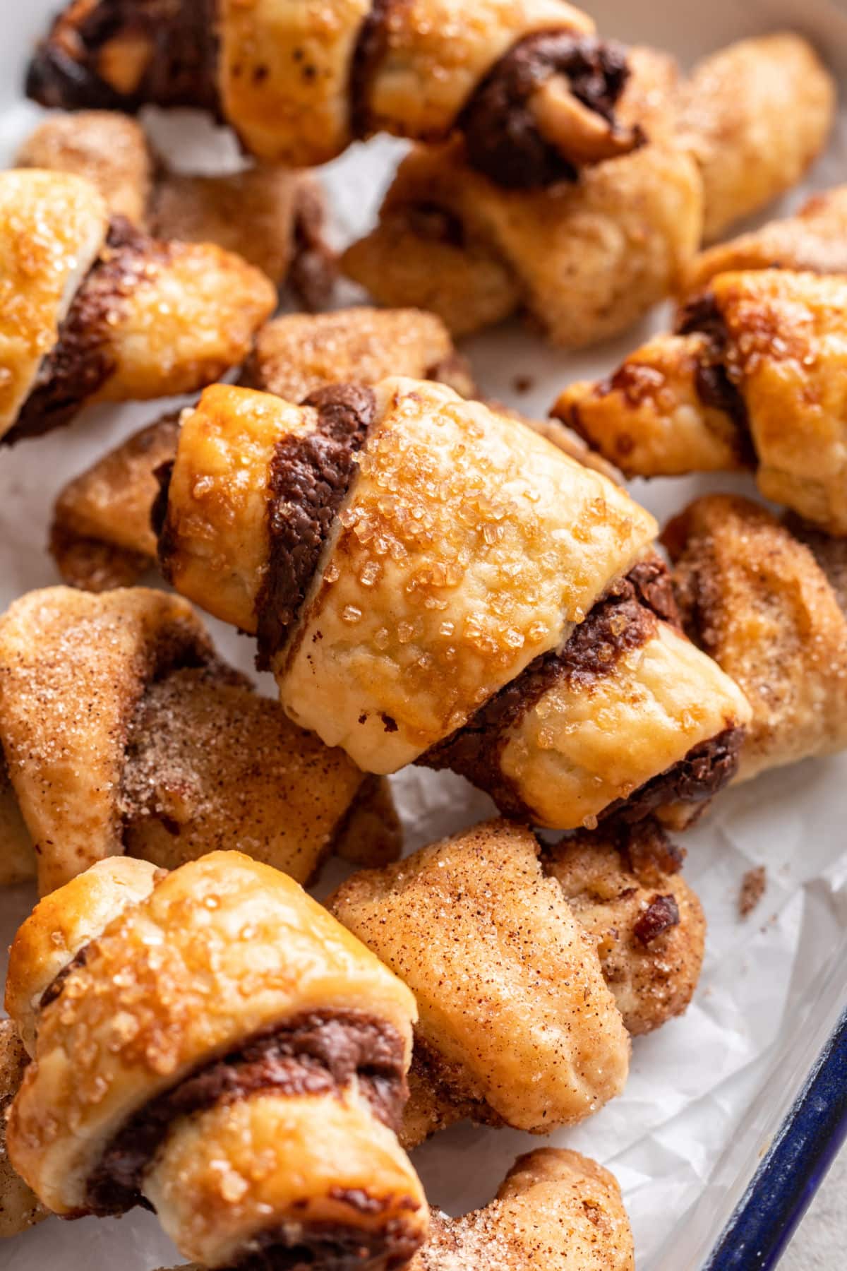 Rugelach Nutella empilés les uns sur les autres dans un plat allant au four tapissé de papier sulfurisé.