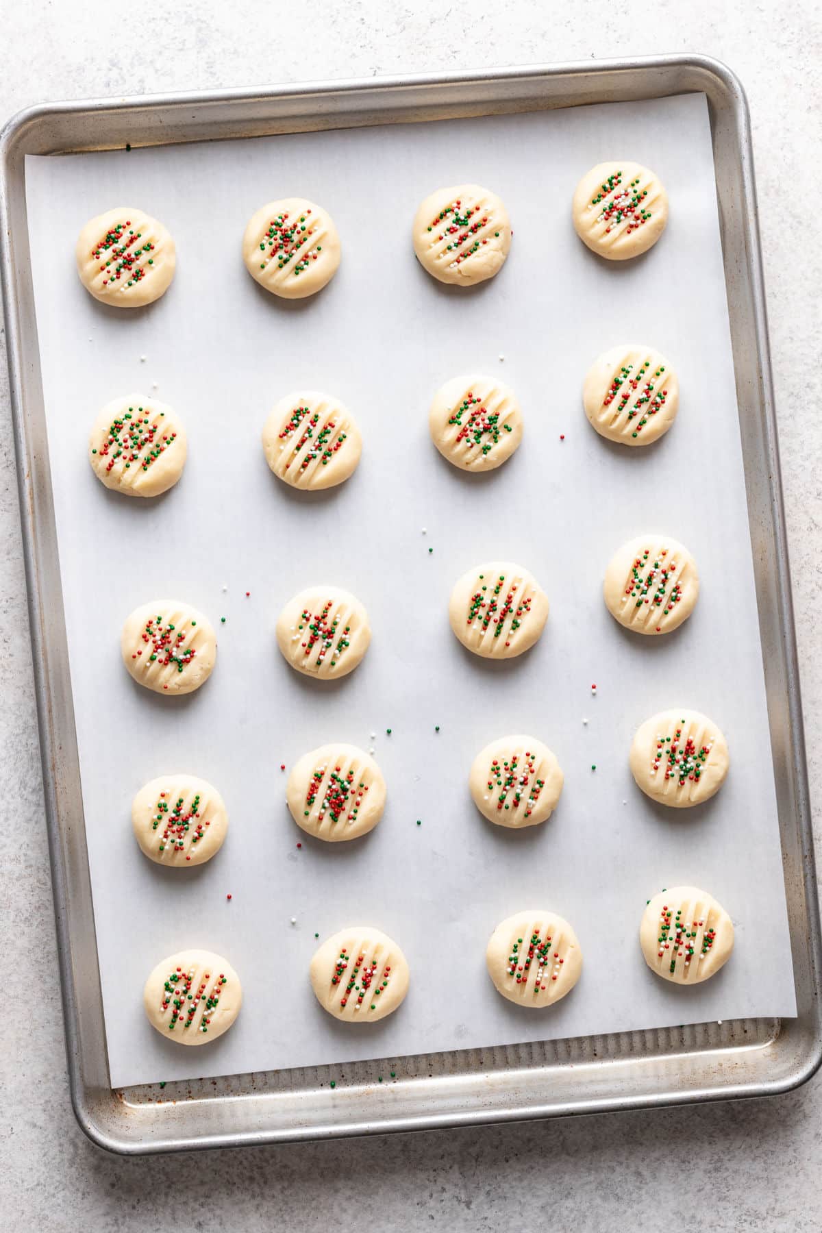 Unbaked whipped shortbread cookies on a baking sheet. 