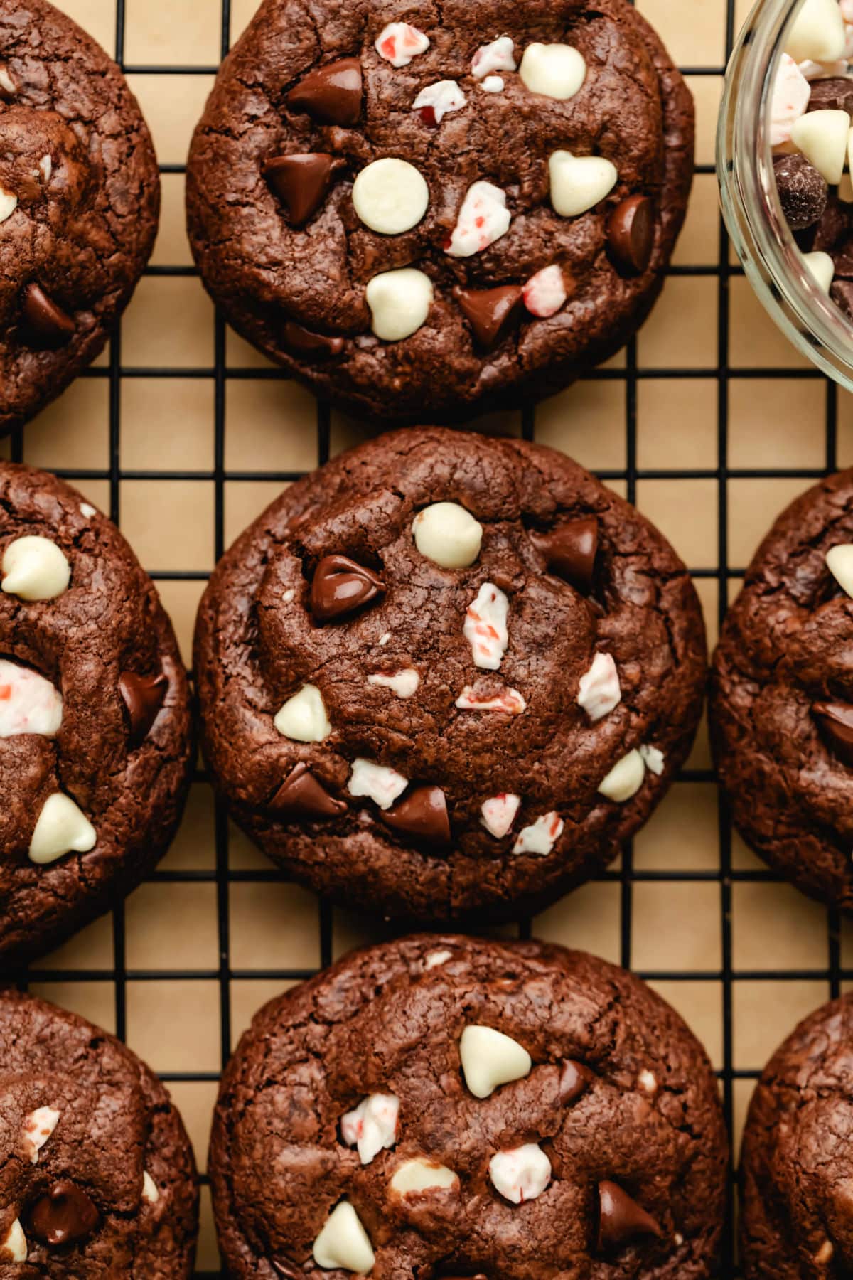 Des rangées de biscuits au chocolat à la menthe poivrée sur une grille de refroidissement noire.