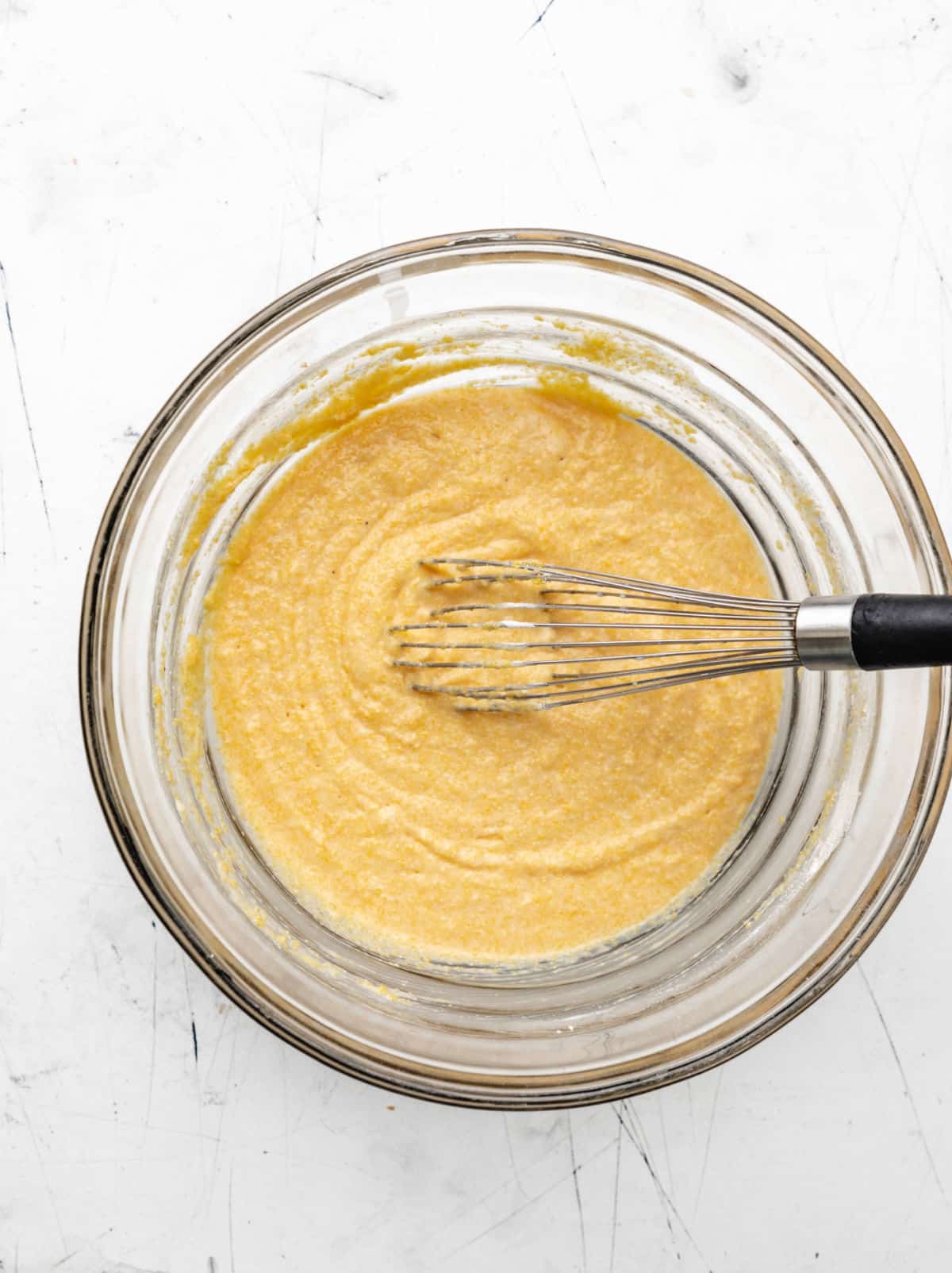 Honey cornbread muffin batter in a glass mixing bowl. 