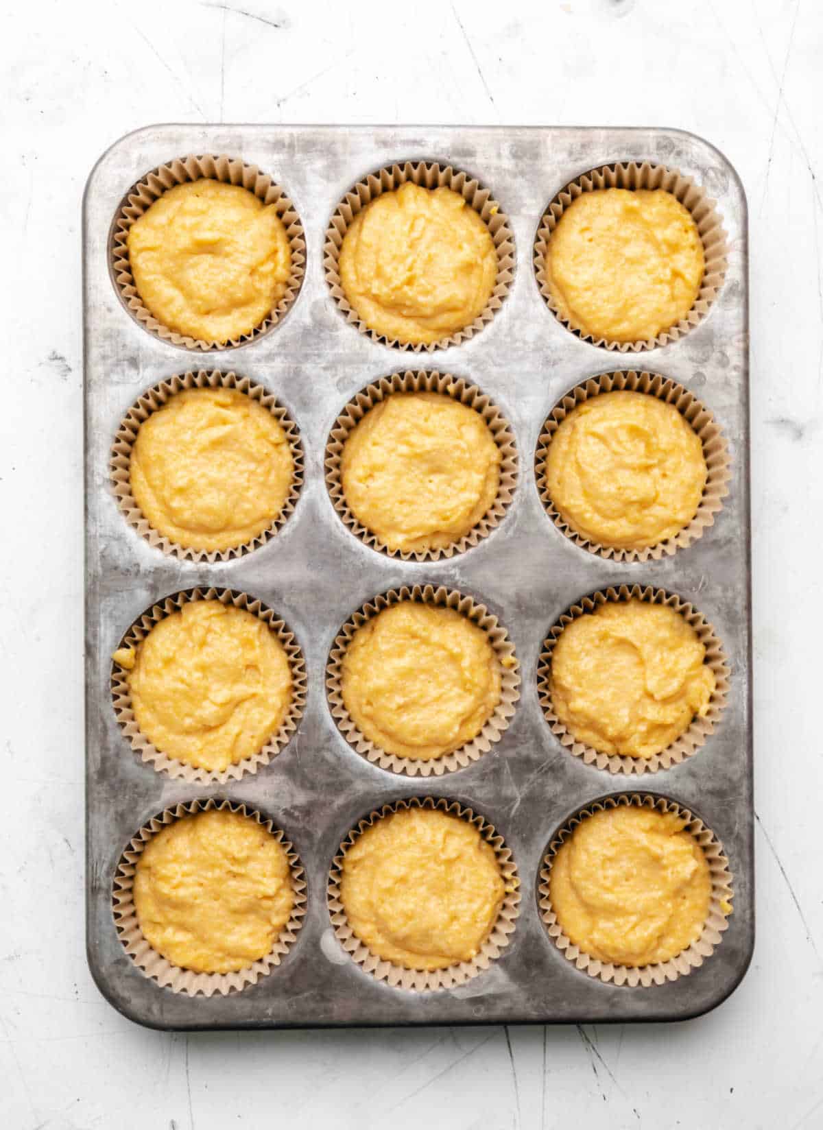 Honey cornbread muffin batter in a muffin tin. 