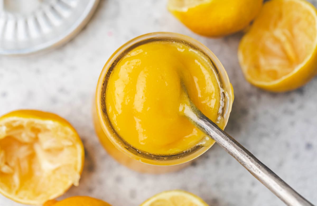 A silver spoon in a jar of lemon curd. 