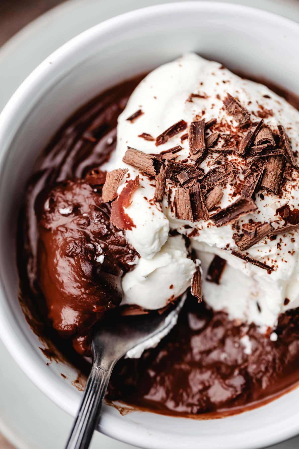 Una cucharada de budín de chocolate con crema batida y virutas de chocolate. 