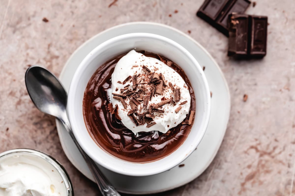 Un plat de pudding au chocolat sur une petite assiette avec une cuillère en argent à côté.