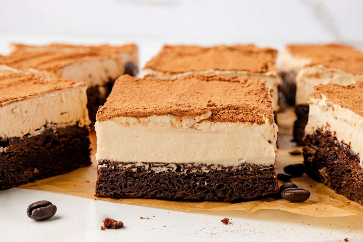 Une rangée de brownies tiramisu sur du papier sulfurisé marron.